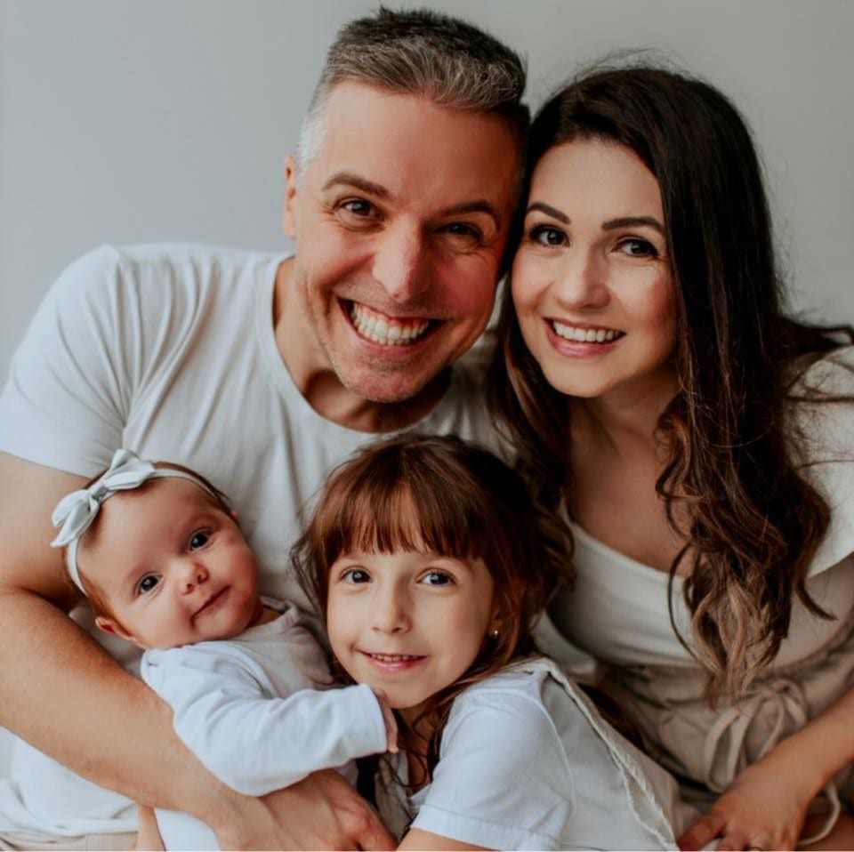 Família reunida em um abraço, com pais e duas crianças